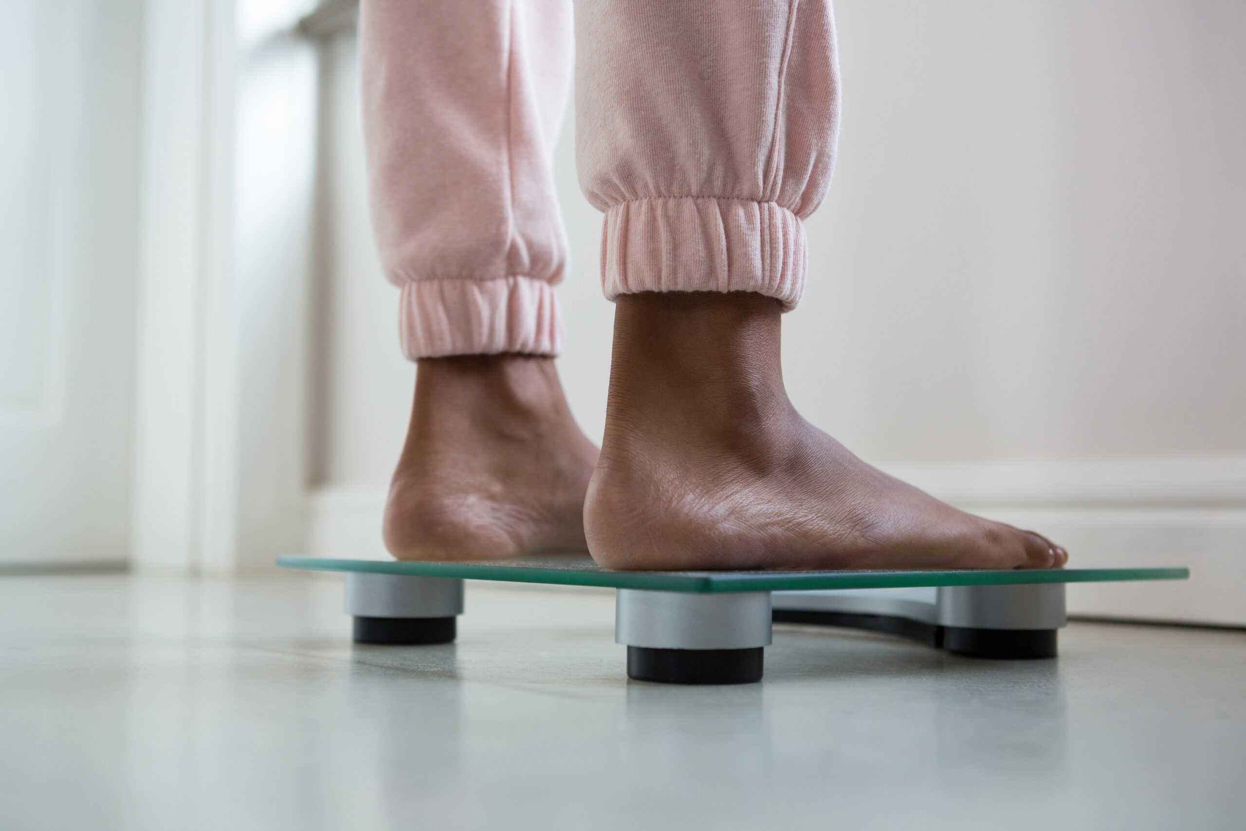 Low section of woman standing on bathroom scale